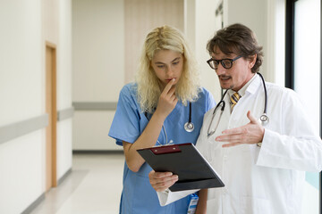 Two medical professionals engaging in a discussion within sanitized hospital corridors