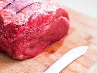 Big size beef top side joint on a wooden cutting board. Premium high quality meat. Traditional meal for a big family dinner. Light and airy look.