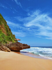 On the edge of Seruni beach, Gunungkidul, Yogyakarta, Indonesia, an angler sits on a large rock.