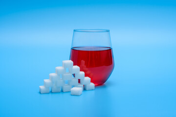 Cukier w kostkach obok szklanki z czerwonym napojem