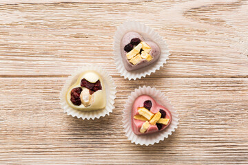 chocolate sweets in the form of a heart with fruits and nuts on a colored background. top view with space for text, holiday concept