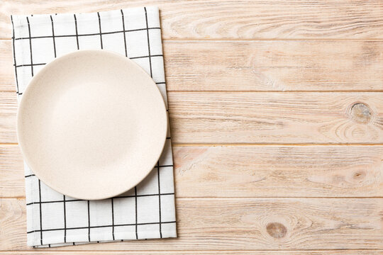 Top view on colored background empty round white plate on tablecloth for food. Empty dish on napkin with space for your design