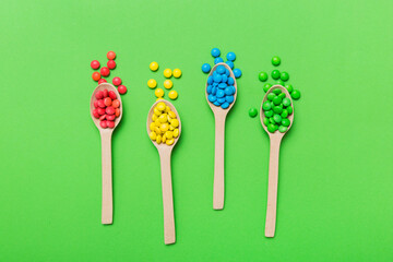 delicious colorful sweet candies on spoon on colored background . Confectionery decor top view with...