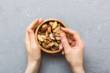 Woman hands holding a wooden bowl with brazil or bertholletia nuts. Healthy food and snack. Vegetarian snacks of different nuts