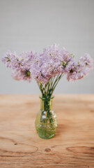 Pinkish white flowers in a glass vase with stems on a wooden table