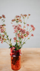 Flowers in an orange glass vase set on a table