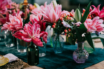 Beautiful flowers in the vases placed on a wooden table.