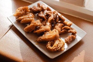 Moroccan chebakias on a white plate in a patio with plants