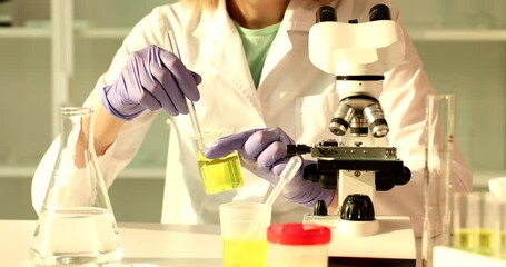 Chemist scientist stirs in hands flask with toxic yellow liquid in chemical laboratory. Analysis of urine or oil products