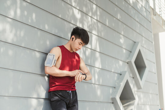 Asian man using app on smart watch for select music, Measure your heartbeat, and calories burned. Fitness, energy and athlete runner doing outdoor cardio workout for good health. - Powered by Adobe