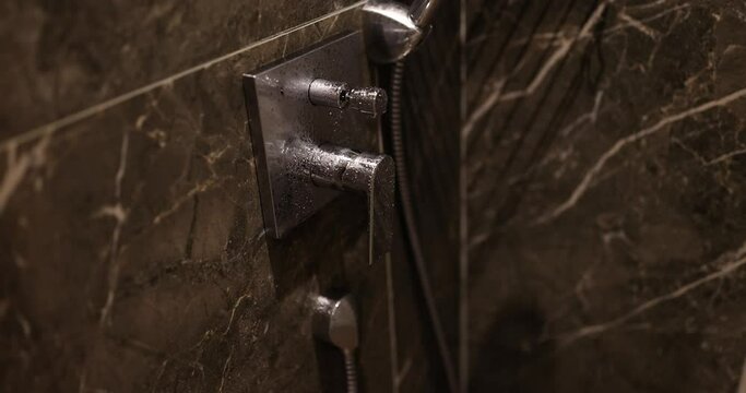 Water faucet with faucet in expensive bathroom. Detail of corner shower enclosure with wall mounted water drop shower