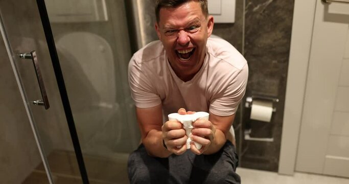 Man suffering from hemorrhoids screams on toilet in toilet. Pain during bowel movements