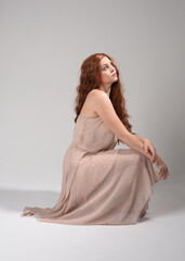 Full length portrait of beautiful brunette model  wearing a creamy pink gown dress. graceful...