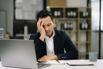 Young stressed Asian businessman working in the office. Businessman thinking too much work concept in the office.
