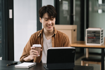 Male are using tablet to work at the desk in the morning.