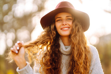 Happy woman with stylish sweater and hat outdoors in autumn park. Woman enjoys autumn nature....
