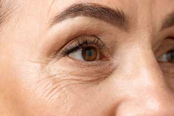 Closeup of middle aged woman eyes. Senior lady looking away, with well-kept and healthy skin. Mimic...