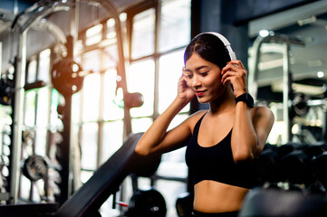 Fototapeta na wymiar Asian woman wearing white workout clothes wearing headphones relax during exercise create energy for exercise fitness inspiration