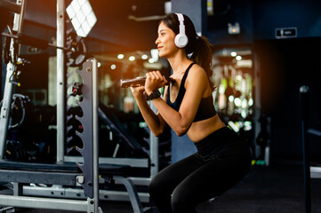 Fototapeta na wymiar lifting dumbbells arm exercises Young woman wearing headphones while exercising Create energy for exercise with exercise music, body weight exercises for a healthy body.