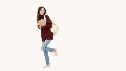 A pretty female college student stands against an isolated white background in a cute, joyful pose.