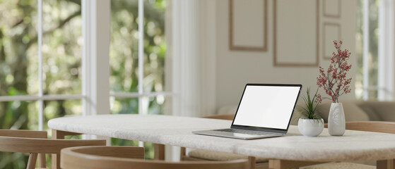 Close-up image of a laptop on a minimal dining table in a modern cozy living room.