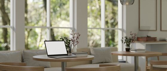 A laptop on a table in a cozy minimalist coffee shop co-working space.