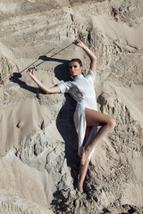 Attractive woman with a sword in a totally white outfit. Fashion shoot in the desert