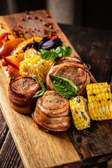 Fried meat medallions with corn, peaches and basil. Serving in a restaurant on a wooden board. place for text.