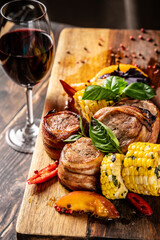 Fried meat medallions with corn, peaches and basil. Serving in a restaurant on a wooden board. place for text.