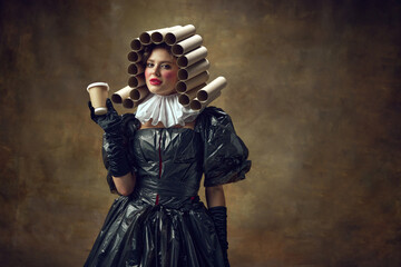 Portrait of woman with bright makeup in paper tube wig dressed in black dress made of garbage bags...