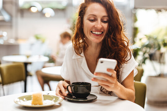 Young woman browsing social media with her smartphone in a restaurant