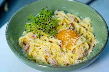A pan filled with pasta and bacon on top of a stove. Delicious pasta dish cooking on the stove. Delicious bowl of pasta with a perfectly cooked egg on top