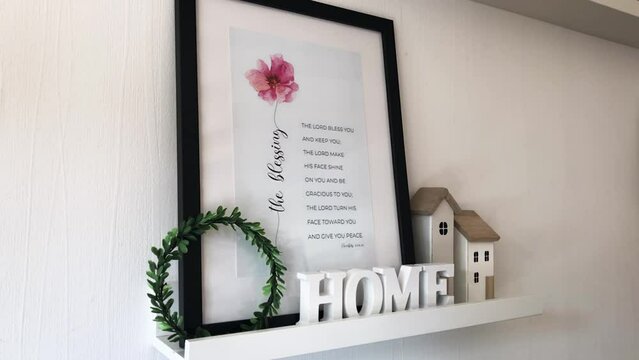 Composition of decor on a white background with a frame, a Christian verse from the Bible and wooden figurines of a house