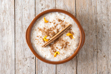 Arroz con leche. Rice pudding with cinnamon in clay bowl on wooden table. Top view