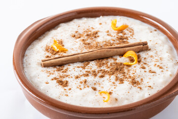 Arroz con leche. Rice pudding with cinnamon in clay bowl isolated on white background