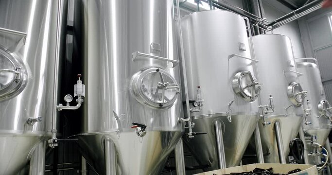 Stainless steel tanks for brewing beer. Huge stainless vats in a brewery. Equipment for beer fermentation. Brewing equipment. Factory, brewery concept. Modern brewery.
