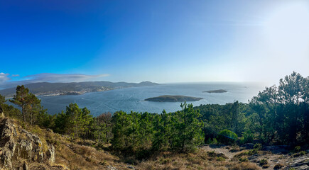 Bathed in golden sunlight, the picturesque Estelas Islands and the charming town of Baiona create a mesmerizing sight from Monteferro's vantage point in Nigrán, Galicia.