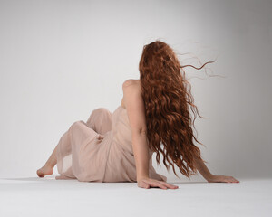Full length portrait of beautiful brunette model  wearing a  pink dress. graceful sitting  pose,...