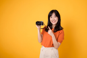 Vibrant woman with a camera isolated on yellow background, showing the adventure of exploring new...