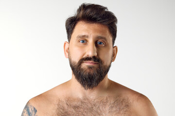Naklejka premium Portrait of handsome bearded mature man with blue eyes posing shirtless against white studio background. Spa. Concept of men's beauty, skin care, cosmetology, health and wellness. Copy space for ad