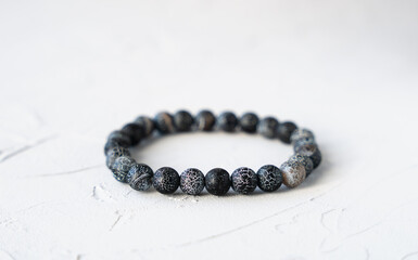 Natural lava stone bracelet on a gray concrete background. Close-up. Copy space.