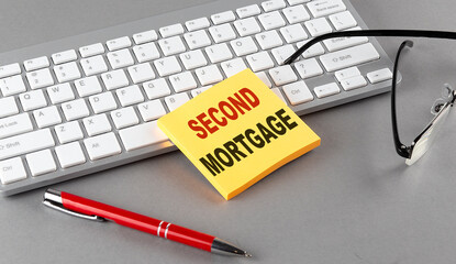 SECOND MORTGAGE text on a sticky with keyboard, pen glasses on grey background