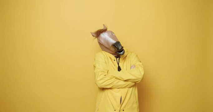 Man with horse mask making funny gestures. Funny Guy in Yellow Suits Dance with Horse Mask, Man having fun on isolated Yellow Background. Having Fun, Party Halloween. April 1, Masquarade idea.
