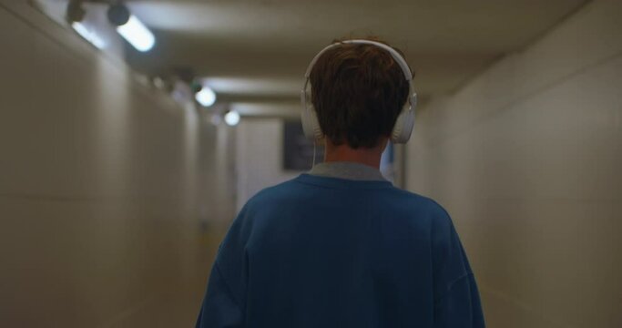 Student listening to music in headphone at city walk, smile, portrait close up slow motion. Teenager walks through the underpass