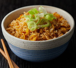 Close up of egg fried rice green onion on top and chopsticks on wood background
