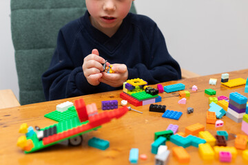 Fototapeta premium A young boy building colored brick toys.