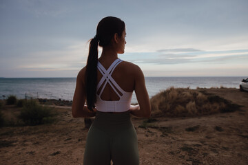 Sport woman looking at the sea horizon at the overcast day, dramatic view