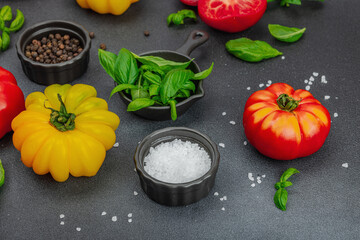 Colorful Heirloom tomato harvest. Ripe ribbed vegetables with fresh basil leaves. Wooden background