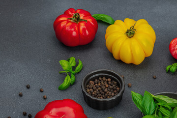 Colorful Heirloom tomato harvest. Ripe ribbed vegetables with fresh basil leaves. Wooden background