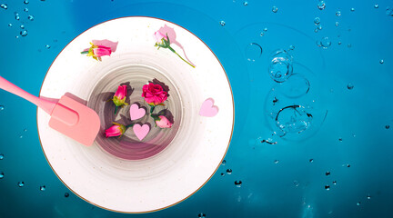 a plate with several roses and two pink hearts on a blue bubble background creative composition flat lay 